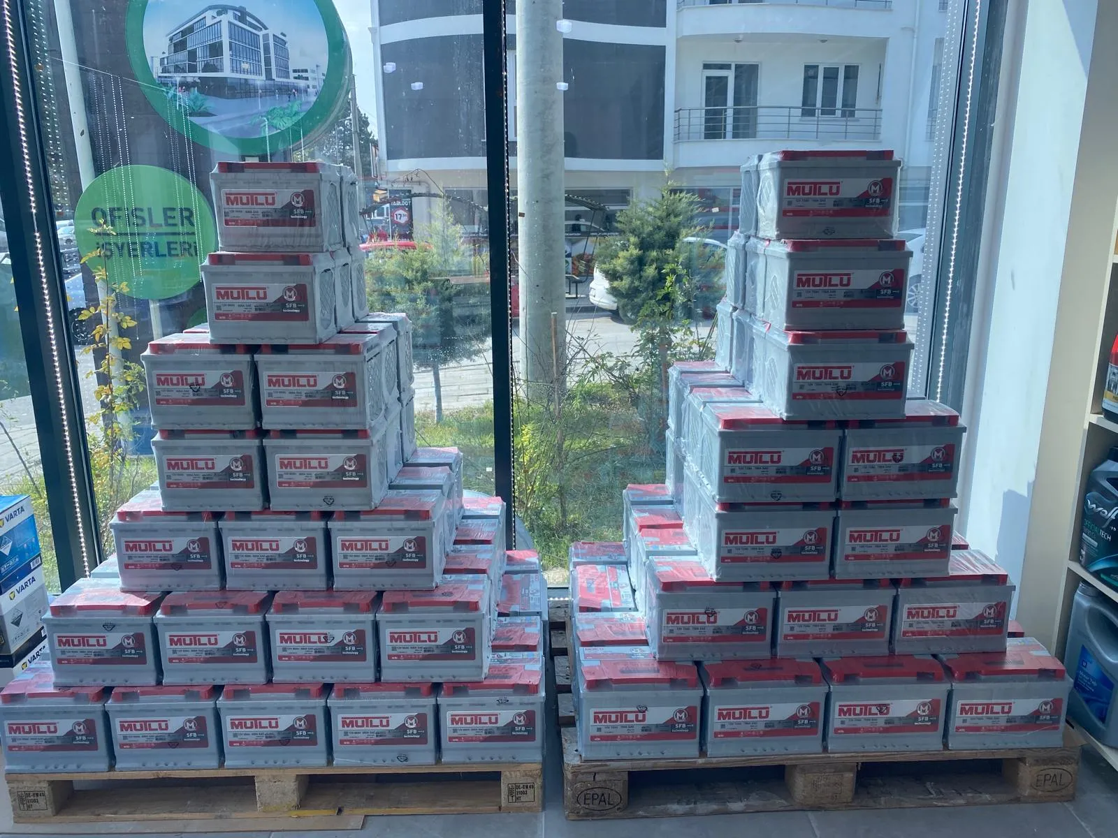 Vitrinde Mutlu akü kutularından piramit istif